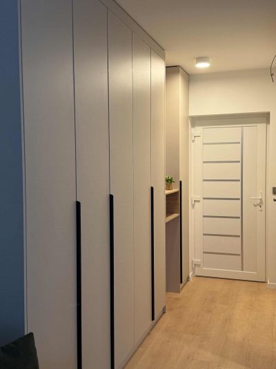 Minimalista bézs előszobabútor extra hosszú fekete fogantyúkkal és tölgy dekor fülkével
